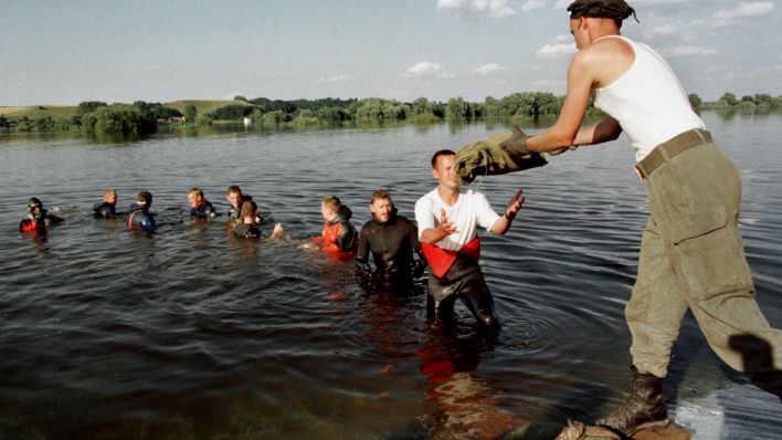 Soldaten und Taucher bilden am 2.8.1997 in der Oder bei Hohenwutzen eine Menschenkette, um Sandsäcke zu transportieren. (Quelle: dpa/Eckehard Schulz)