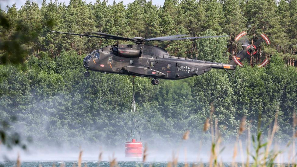 Ein Bundeswehrhubschrauber vom Typ Bell CH-53 holt Löschwasser zur Waldbrandbekämpfung aus dem Kiebitzer Baggerteich. (Quelle: dpa/Jan Woitas)