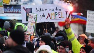 15.01.2024, Berlin: Ein Bengalo brennt während einer Protestdemonstration vor dem Brandenburger Tor vor einem Schild mit der Aufschrift "Schluss mit gehampel". (Quelle:dpa/S.Gollnow)