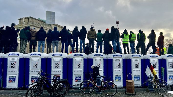 Protestierende Bauern stehen vor dem Brandenburger Tor in Berlin Tiergarten auf aufgereihten TOI-TOI-Toiletten. (Quelle: Eva Leytz)