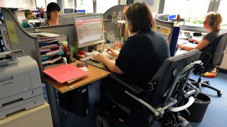 Symbolbild: Eine im Rollstuhl sitzende Frau arbeitet als Telefonserviceberater im Servicecenter. (Quelle: dpa/Waltraud Grubitzsch)