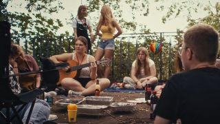 In einer Filmszene sitzen Jugendliche in einem Park und grillen, eine Jugendliche spielt Gitarre (Foto: Lusatia Film)