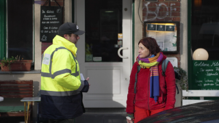 Ein Infopoint-Mitarbeiter in gelber Weste im Gespräch mit einer Frau (Quelle: rbb)