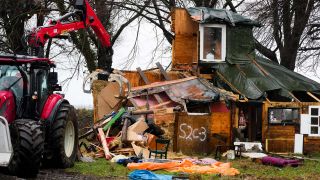 Ein Bagger zerstÃ¶rt ein Holzhaus von Besetzern des Ortes LÃ¼tzerath, die gegen das Abbaggern von Kohle demonstrieren. (Bild: dpa)