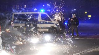 Polizeibeamte stehen hinter explodierendem Feuerwerk.