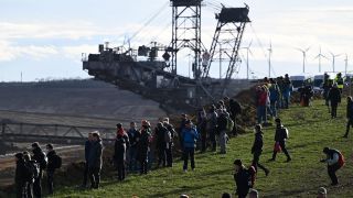 Klimaschutzaktivisten stehen vor einem Schaufelradbagger am Rand des Tagebaus in LÃ¼tzerath