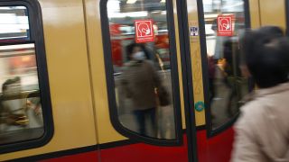 Rote Schilder weisen auf der S-Bahn Tür auf die Pflicht zum Tragen einer Maske hin.