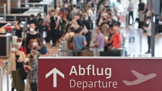 Reisende warten an einem Check-in fÃ¼r ihren Abflug vom Hauptstadtflughafen Berlin Brandenburg (BER).