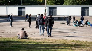 Archivbild: Asylsuchende laufen in der Erstaufnahmeeinrichtung EisenhÃ¼ttenstadt Ã¼ber einen Platz. 