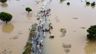 Menschen in Nigeria laufen nach heftigen RegenfÃ¤llen durch Flutwasser (Bild: dpa)