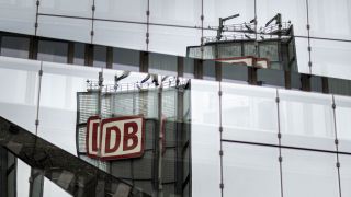 Das Logo der Deutschen Bahn spiegelt sich in einer Glasfassade in Berlin