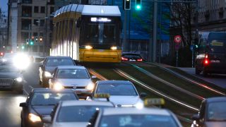 Eine Berliner Tram Ã¼berholt Autos, die im Stau stehen.