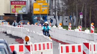 Eine Fahrradfahrerin fÃ¤hrt auf einem durch eine Baustelle fÃ¼hrenden provisorischen Radweg, der fÃ¼r FuÃgÃ¤nger und Radfahrer eingerichtet wurde. 