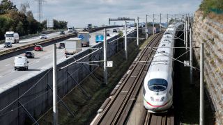 Ein ICE der Deutschen Bahn faehrt mit Hochgeschwindigkeit an Autos auf der Autobahn A3 vorbei (Bild: picture alliance)