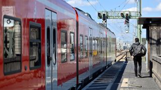 Ein Mann geht ein Gleis entlang, an dem eine S-Bahn der Deutschen Bahn steht.