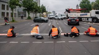 Bei einer StraÃenblockade der Letzten Generation sitzen Aktivisten auf dem MÃ¼hlendamm auf der StraÃe