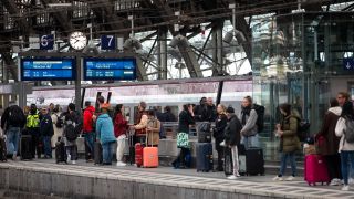 Bahnreisende warten auf dem Bahnsteig auf die Einfahrt eines Zuges im KÃ¶lner Hauptbahnhof.