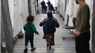 FlÃ¼chtlinge sind in einem Zelt einer provisorischen FlÃ¼chtlingsunterkunft unterweg