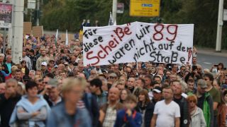 Teilnehmer einer Demo, bei der ein Transparent mit der Aufschrift 