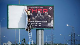 Ein Mann nimmt an einer Autobahn am Stadtrand von St. Petersburg das Plakat mit der Aufschrift 