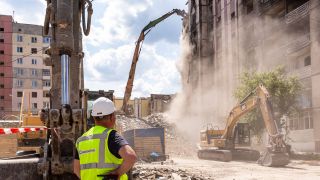 Bagger sind im Einsatz beim Wiederaufbau eines Wohnblocks in der Ukraine.