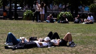 Touristen liegen erschÃ¶pft von der Hitze im Lustgarten auf der Museumsinsel in Berlin.