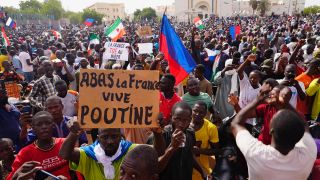 Menschen halten Plakate und Fahnen wÃ¤hrend sie an einem Marsch teilnehmen, zu dem AnhÃ¤nger des Putschisten General Omar Tchiani im Niger aufgerufen haben.