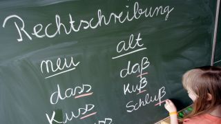 Eine SchÃ¼lerin einer Grundschule schreibt die jeweils neuen und alten Schreibweisen von WÃ¶rtern an eine Tafel.