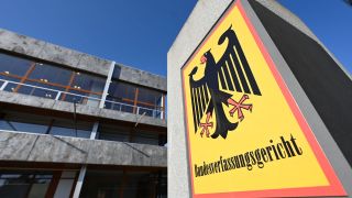 Vor dem Bundesverfassungsgericht hÃ¤ngt ein Hinweisschild mit der Aufschrift Bundesverfassungsgericht und dem Bundesadler.