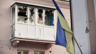 Ein durch russischen Beschuss zerstÃ¶rter Balkon ist in Isjum hinter einer ukrainischen Flagge zu sehen.