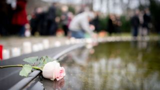 Eine Rose liegt bei einer Gedenkveranstaltung am Denkmal fÃ¼r die im Nationalsozialismus ermordeten Sinti und Roma Europas am Rande des Wasserbeckens.