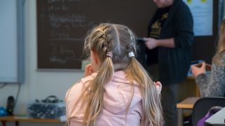 Ein MÃ¤dchen sitzt in seinem Klassenraum und verfolgt den Unterricht. 