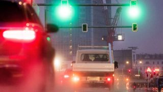 Autos und ein Motorrad fahren an eine Ampelkreuzung am Alexanderplatz.