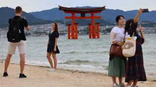 Junge Menschen machen Handy-Fotos vor dem Itsukushima-Schrein, ein Unesco-Weltkulturerbe in Japan.