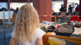 Ein Kind Emilya steht in einer Ausgabestelle der Berliner Tafel an einem Tisch mit Spielzeug.