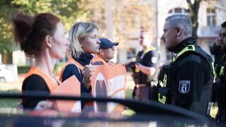 Aktivisten und Aktivistinnen stehen wÃ¤hrend einer Laufblockade der Klimaschutzgruppe Letzte Generation auf der Bornholmer StraÃe am 21. September vor Polizeibeamten.