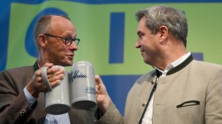 Friedrich Merz (l), Bundesvorsitzender der CDU, und Markus SÃ¶der (CSU), MinisterprÃ¤sident von Bayern, stoÃen beim Politischen FrÃ¼hschoppen Gillamoos auf der BÃ¼hne mit BierkrÃ¼gen an.