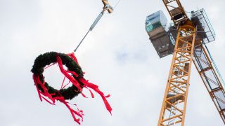 Ein Kranz hÃ¤ngt beim Richtfest vor einem Neubauprojekt