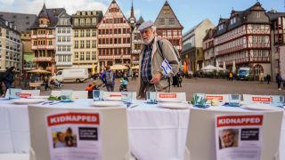 Ein Mann mit israelischer Nationalflagge geht an der Tischreihe mit Fotos von mutmaÃlichen Hamas-EntfÃ¼hrungsopfern entlang. Die JÃ¼dische Gemeinde Frankfurt macht mit der Installation auf die Situation der mutmaÃlich von der Terrororganisation Hamas entfÃ¼hrten Menschen aufmerksam. Auf dem RÃ¶merberg steht eine lange, mit Geschirr eingedeckte Schabbat-Tischtafel, mit 222 leeren StÃ¼hlen. Auf den StÃ¼hlen sind Fotografien und Namen der EntfÃ¼hrten angebracht.