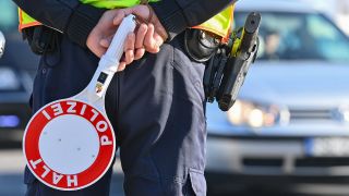 Ein Beamter der Bundespolizei steht am deutsch-polnischen GrenzÃ¼bergang mit einer Kelle mit der Aufschrift 