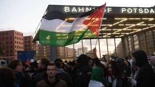 Menschchen stehen bei einer verbotenen Pro-PalÃ¤stina-Demonstratin am Potsdamer Platz.Â Eine Frau hÃ¤lt dabei eine PalÃ¤stinenser-Fahne. (Bild: picture alliance/dpa | Paul Zinken)