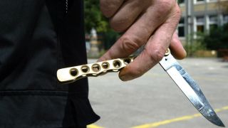 Symbolfoto: Ein SchÃ¼ler hÃ¤lt ein Butterlymesser auf einem Schulhof in der Hand.