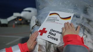 HilfsgÃ¼ter werden auf dem Flughafen Leipzig-Halle mit einem Aufkleber des Deutschen Rotes Kreuzes markiert.