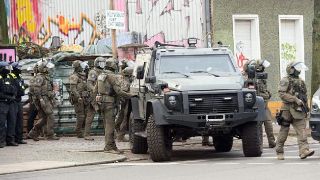  Polizisten stehen bei einem gepanzerten Fahrzeug am Markgrafendamm in Berlin