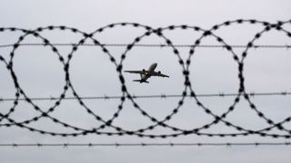 Symbolbild Abschiebung: Flugzeug durch Stacheldrahtzaun