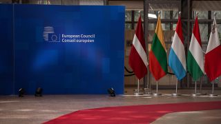 Der Empfangsbereich des Europäischen Rates in Brüssel mit Logo des Europäischen Rates, einigen Flaggen der Mitgliedstaaten sowie dem Roten Teppich.