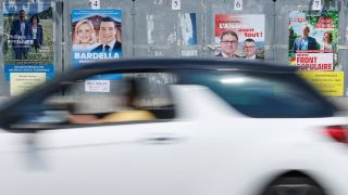 Ein Auto fÃ¤hrt an Wahlplakaten in Frankreich vorbei