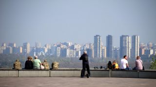 Am linken Ufer des Dnipro-Flusses sitzen Menschen auf einem Felsvorsprung gegenÃ¼ber den HochhÃ¤usern in der ukrainischen Hauptstadt Kiew.