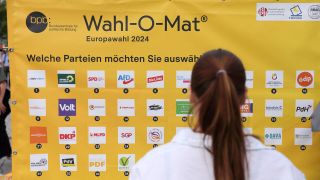 Eine Person steht vor einem analogen Wahl-O-Mat zum Aufkleben zur Europawahl 2024 beim Europafest auf dem Alten Markt in Potsdam.