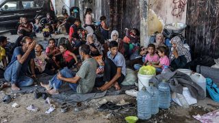 Erwachsene und Kinder sitzen in Chan Junis auf einer StraÃe. 